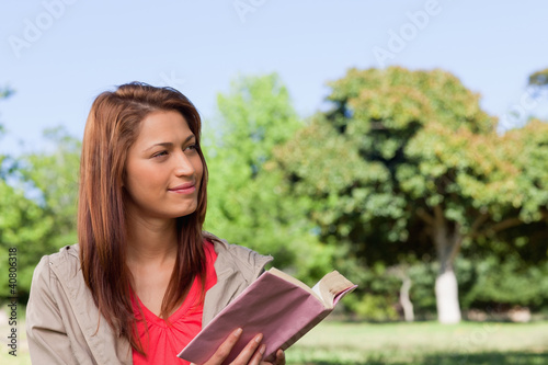 Photo: Woman smirking towards the side while reading a book Woman smirking towards the side while reading a book