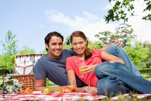 Photo: Two friends looking ahead while they hold glasses as they lie on Two friends looking ahead while they hold glasses as they lie on