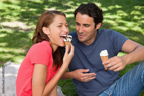 Photo: Woman eating ice cream while sitting with her friend Woman eating ice cream while sitting with her friend