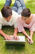 Two friends looking at something on a laptop while lying down