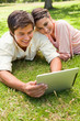 Woman leans against her friend as they use a tablet together