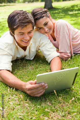Photo: Woman leans against her friend as they use a tablet together Woman leans against her friend as they use a tablet together