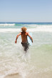 Young blonde man holding his blue surfboard while running in the