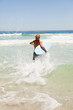 Blonde man running fast in the water while holding his surfboard