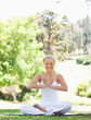 Photo: Smiling woman sitting in the park in a yoga position Smiling woman sitting in the park in a yoga position