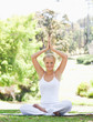 Smiling woman sitting in a yoga position on the grass