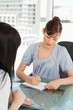 canvas print picture - As her co-worker chats the brunette employee writes on her note
