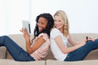 Photo: A woman leaning up against her friends back is holding a tablet A woman leaning up against her friends back is holding a tablet