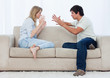 A couple sitting on a couch are having an argument