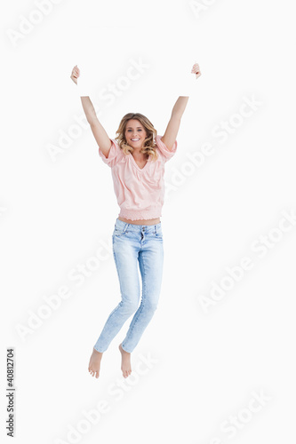 Foto: Smiling young woman jumping while holding a blank poster Smiling young woman jumping while holding a blank poster