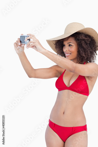 Photo: Young woman in beachwear photographing herself Young woman in beachwear photographing herself