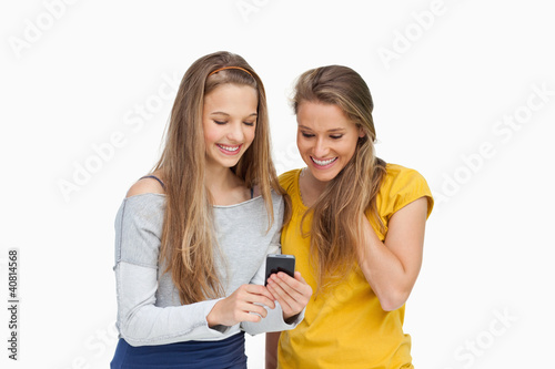 Photo: Two smiling students looking a cellphone screen Two smiling students looking a cellphone screen