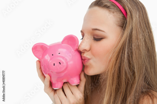 Foto: Close-up of a young woman kissing a piggy-bank Close-up of a young woman kissing a piggy-bank