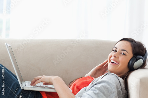 Photo: Laughing woman ying on the couch while looking at the camera Laughing woman ying on the couch while looking at the camera