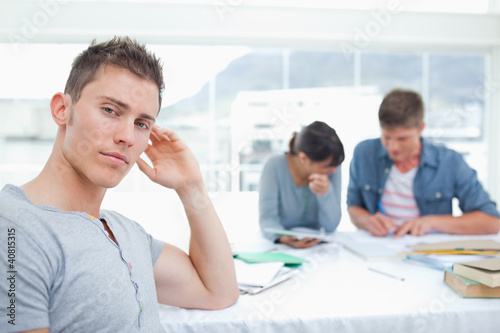 Photo: A serious looking student with his hand on his head looks into t A serious looking student with his hand on his head looks into t