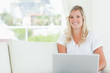 A smiling woman holding a laptop as she looks at the camera