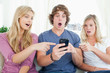 People on the couch shocked at what is on the phone