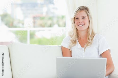 Photo: A smiling woman holding a laptop as she looks at the camera A smiling woman holding a laptop as she looks at the camera