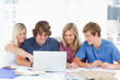 A female student points to the screen as the group use the lapto