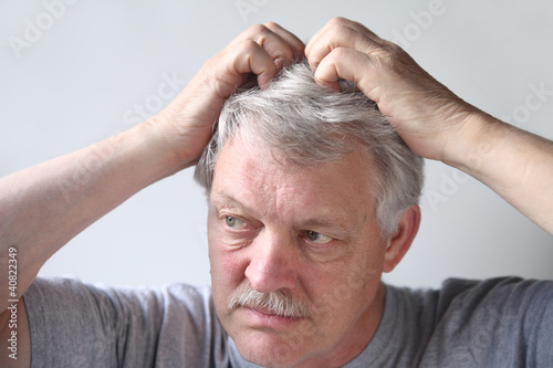Photo: mature man uses both hands to scratch his head mature man uses both hands to scratch his head