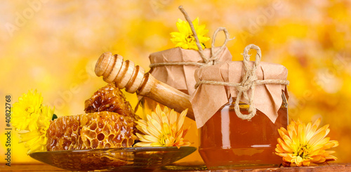 Photo: two jars of honey,honeycombs and wooden drizzler two jars of honey,honeycombs and wooden drizzler