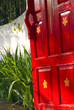Bright red wooden gate leading to a lush garden