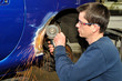 Car body worker grinding metal.