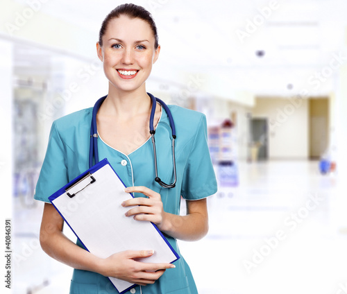 Photo: Smiling female medical doctor with clipboard in a corridor of a Smiling female medical doctor with clipboard in a corridor of a