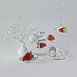 Flying strawberries with white ribbon and decorative dishes.