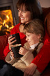 Mother And Daughter Relaxing With Hot Drink Watching TV By Cosy