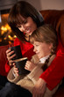 Mother And Daughter Relaxing With Hot Drink Watching TV By Cosy
