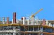 Building crane and building under construction against blue sky