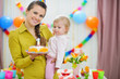 Mother holding baby and birthday party cake