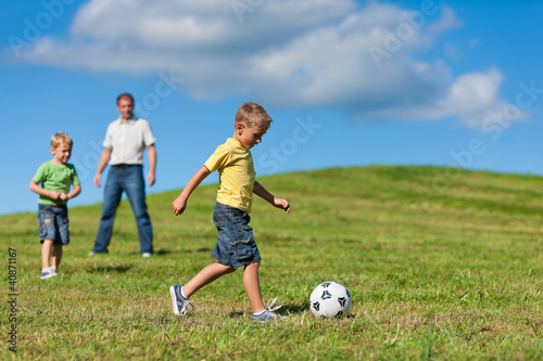 Photo: Glückliche Familie spielt Fußball im Sommer Glückliche Familie spielt Fußball im Sommer
