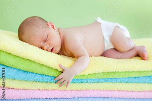 Photo: newborn baby girl weared cap sleeping on colourful towels newborn baby girl weared cap sleeping on colourful towels