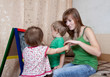 Woman and children draws on  blackboard