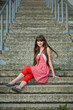 Beautiful girl in a red dress sitting on the gray concrete steps Beautiful girl in a red dress sitting on the gray concrete steps