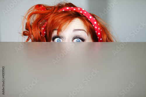 Photo: Funny girl hiding behind a table Funny girl hiding behind a table