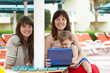 happy girls with laptop at resort happy girls with laptop at resort