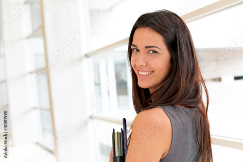 Photo: Young businesswoman in modern building holding files Young businesswoman in modern building holding files