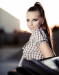 Beautiful blond model sitting on old car at night shot