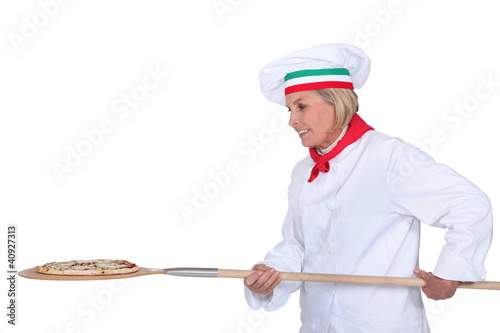 Photo: Italian chef putting a pizza in the oven Italian chef putting a pizza in the oven