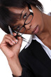 Businesswoman with pen lifting glasses frame
