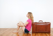 Girl dreaming of vacation, sitting next to her suitcase