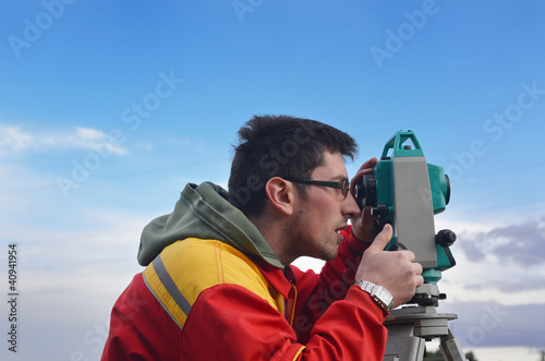 Photo: One surveyor worker working with theodolite transit equipment at One surveyor worker working with theodolite transit equipment at