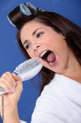 Photo: Woman with curlers and toothbrush in hand singing Woman with curlers and toothbrush in hand singing