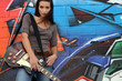 Female guitarist stood by graffiti