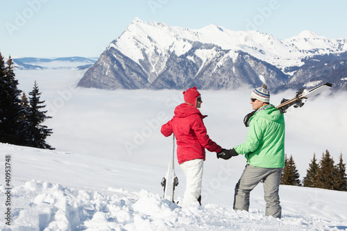 Photo: Couple Admiring Mountain View Whilst On Ski Holiday In Mountains Couple Admiring Mountain View Whilst On Ski Holiday In Mountains