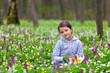 Cute little girl picking flowers in the spring forest