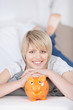 lachende blonde frau mit sparschwein